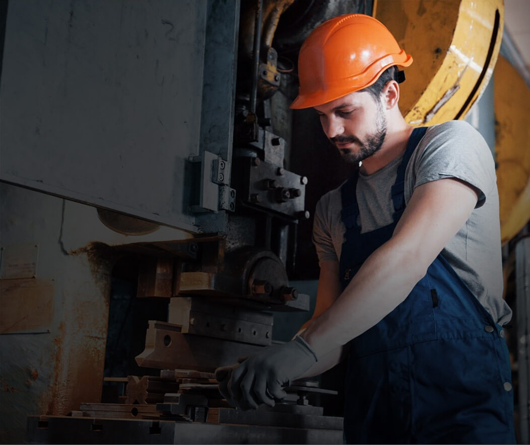 Travailleur manipulant une pièce sur une presse hydraulique dans un atelier de fabrication